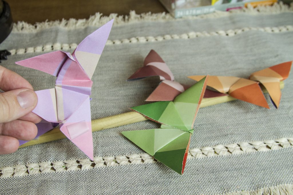 taping oragami butterflies onto a dowell rod
