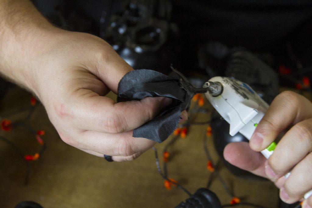 hot gluing fake black flowers to the halloween wreath